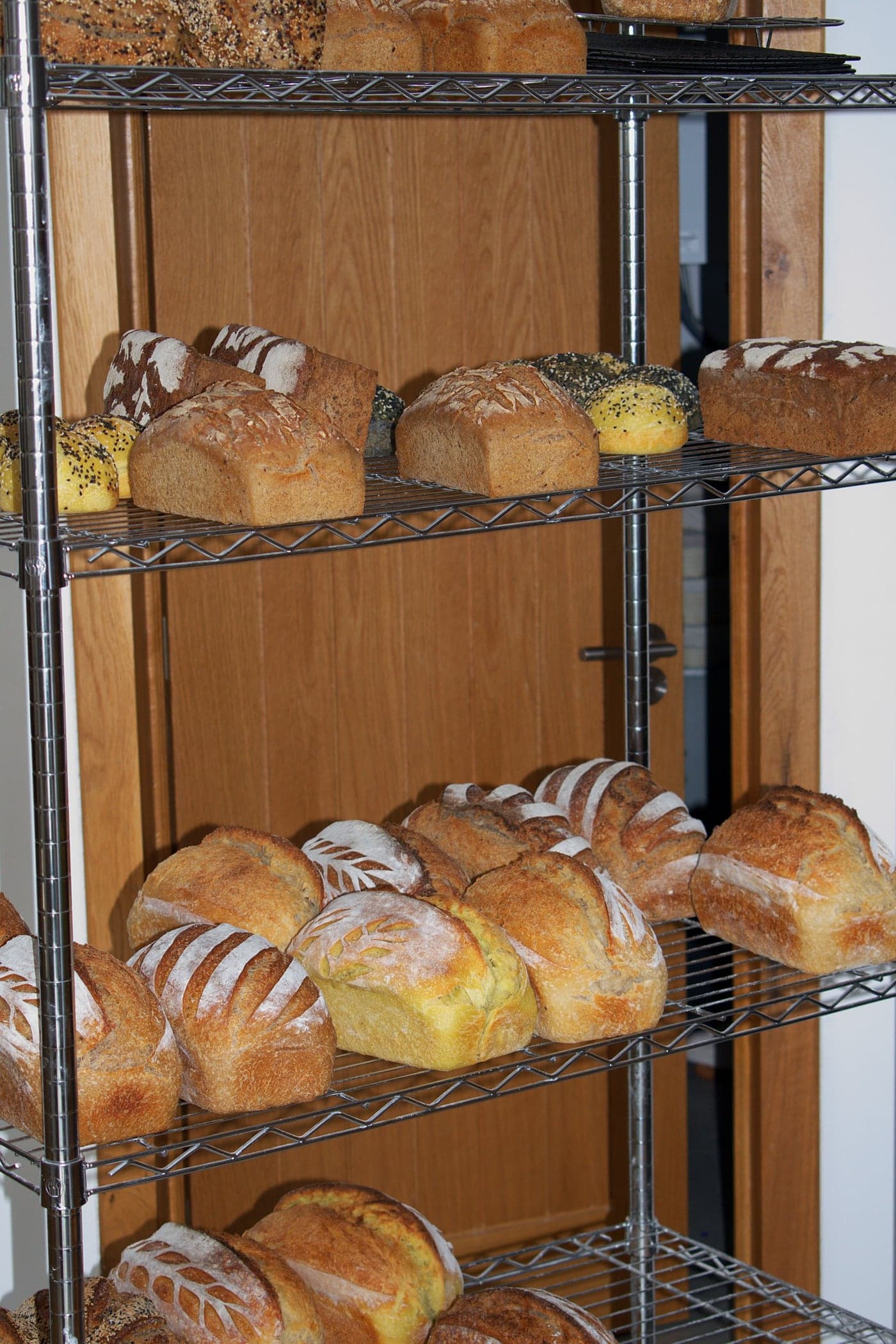 Different kinds of bread on the metal shelves in the bakery.