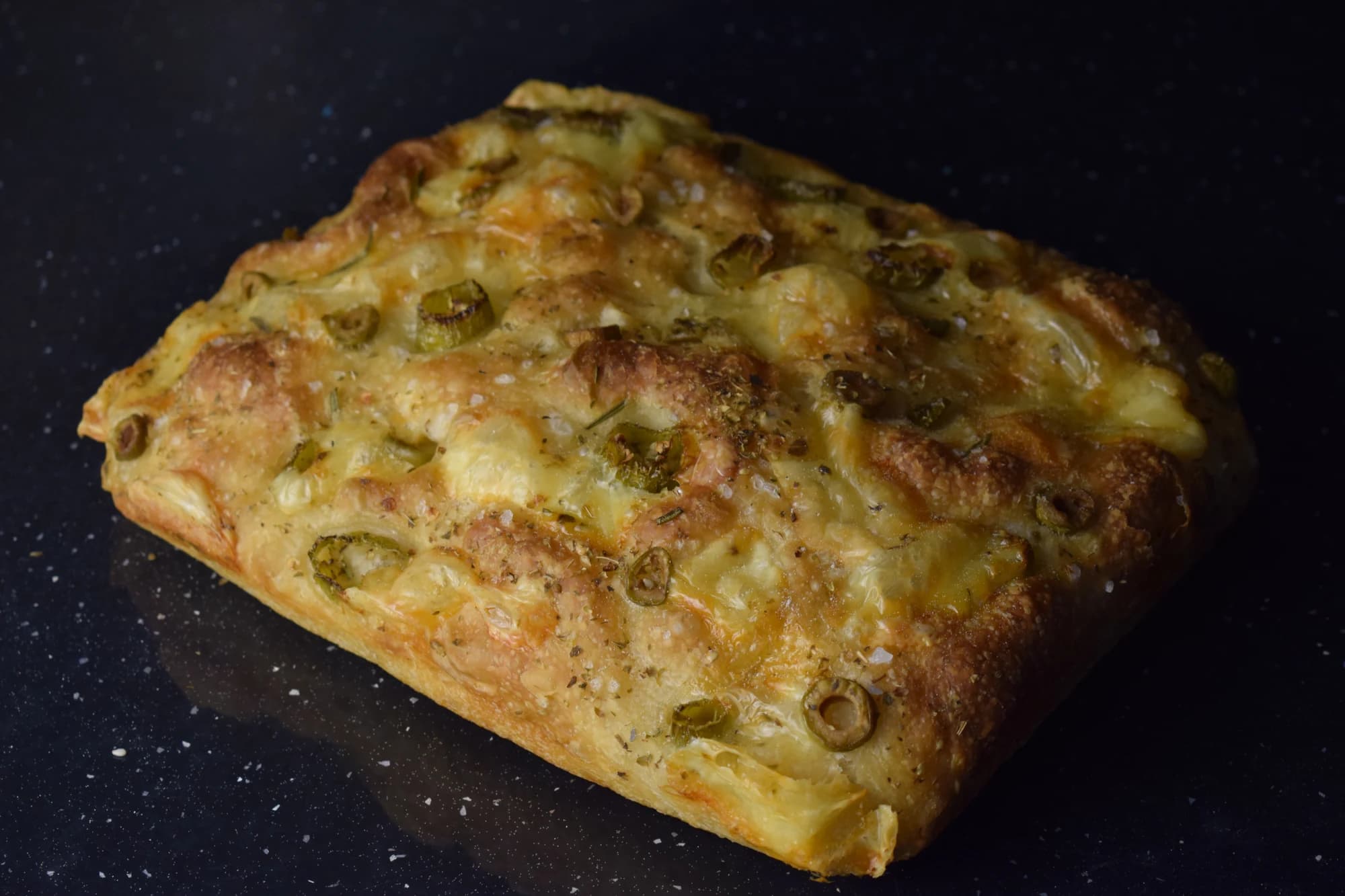 Focaccia cu maia cu măsline, pe un fundal cald.