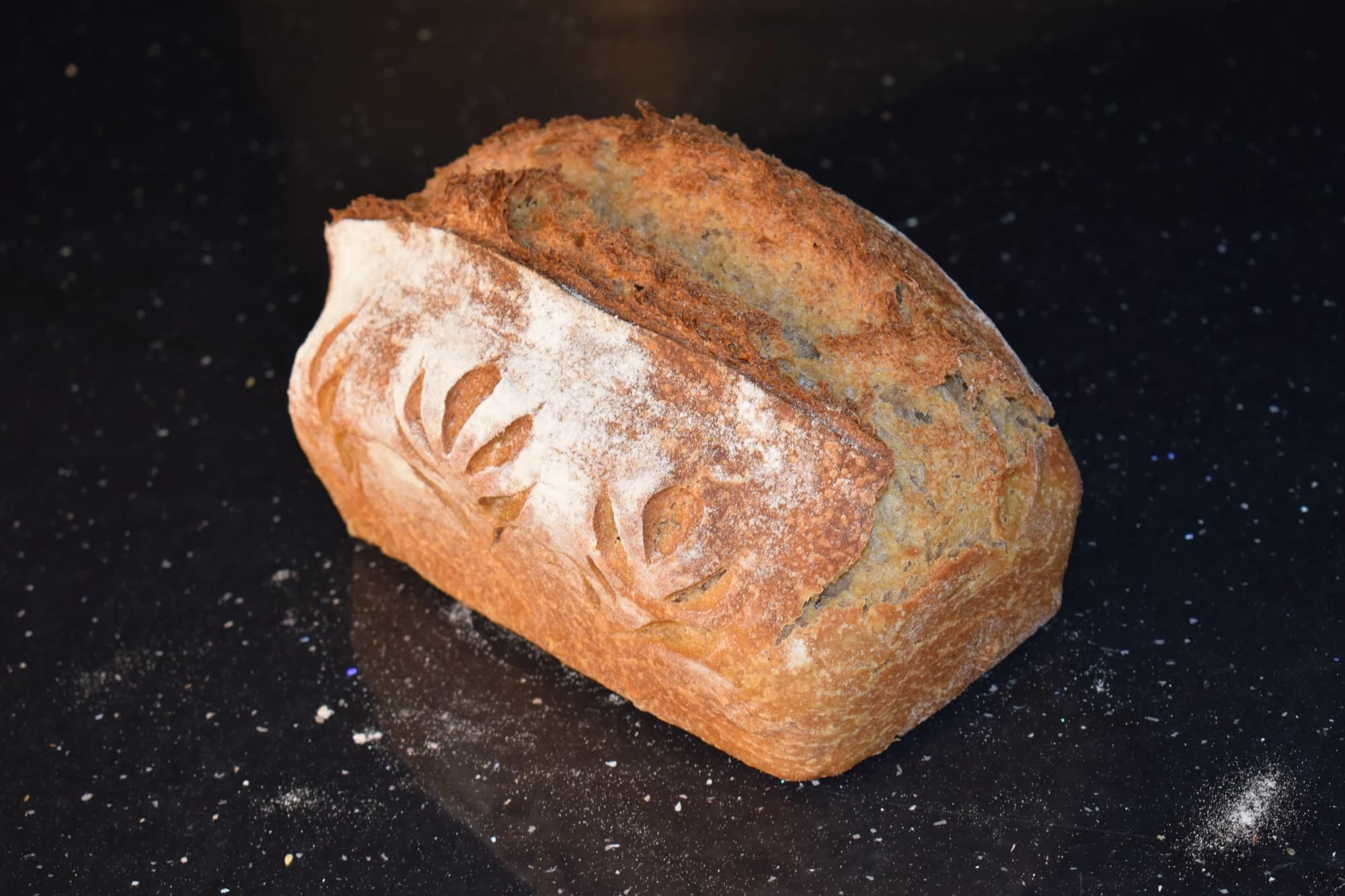 Pâine de spelta crestată, pe un blat negru.