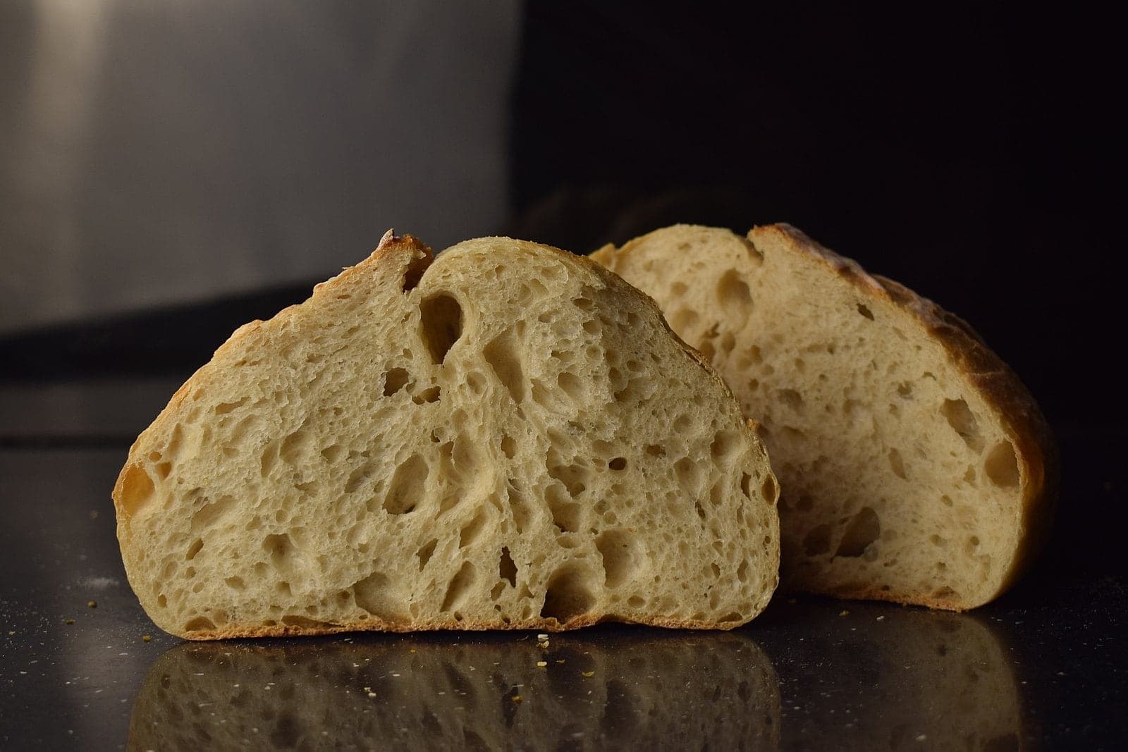 A loaf cut in half, showing its airy crumb with large holes.